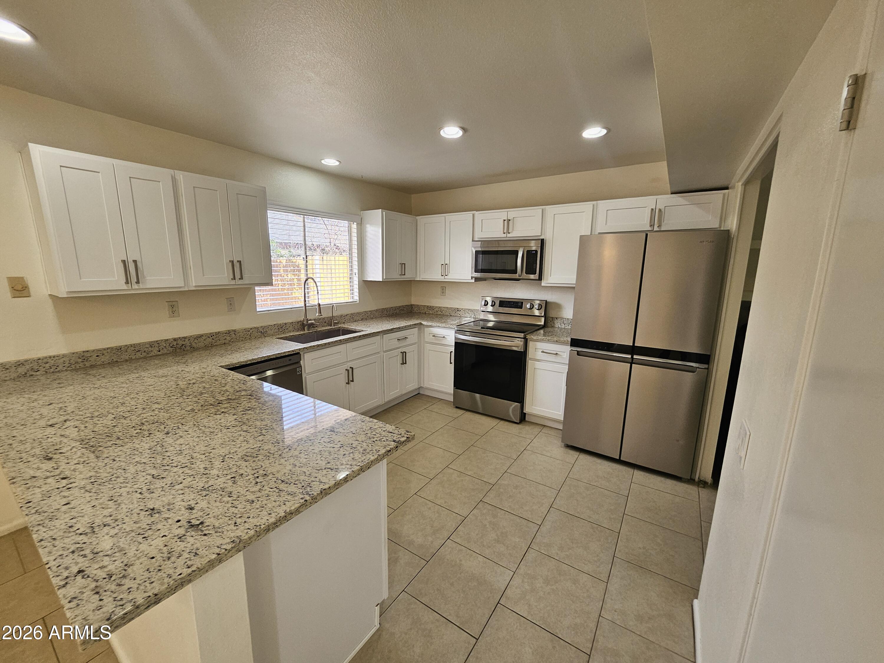 7038 South 42nd Street Phoenix, AZ 85042 - Photo 8 of 22 a kitchen with granite countertop a refrigerator a sink and white cabinets