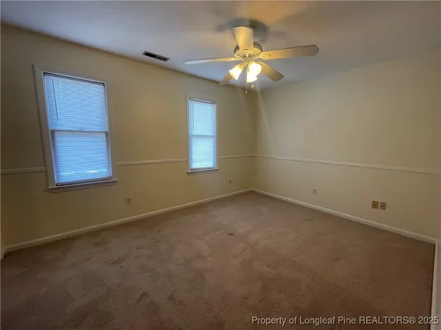 en empty room with windows and chandelier fan