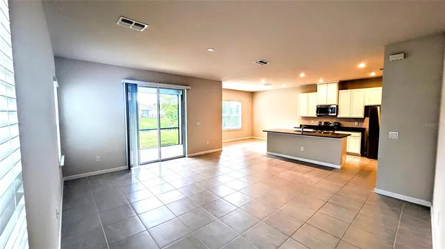 a view of kitchen with stainless steel appliances wooden floor and window