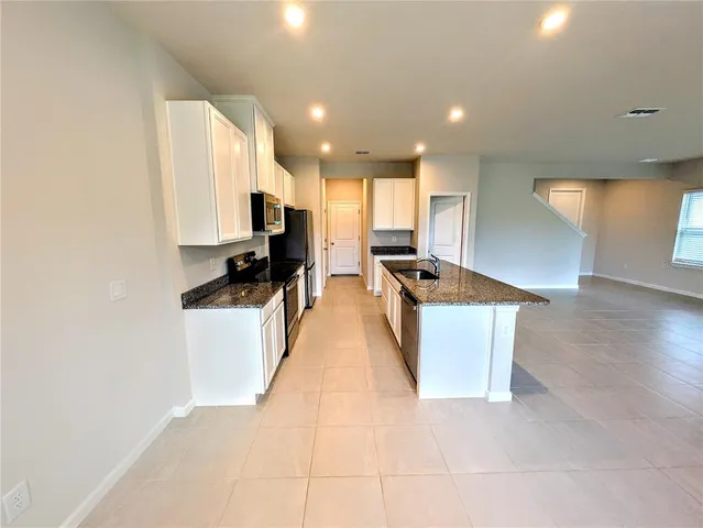 a kitchen with stainless steel appliances granite countertop a stove a sink and a microwave