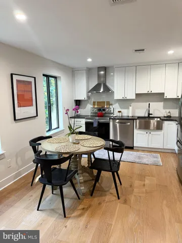 a kitchen with stainless steel appliances kitchen island granite countertop a table chairs sink and cabinets