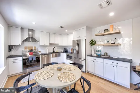 a kitchen with refrigerator a stove a sink dining table and chairs