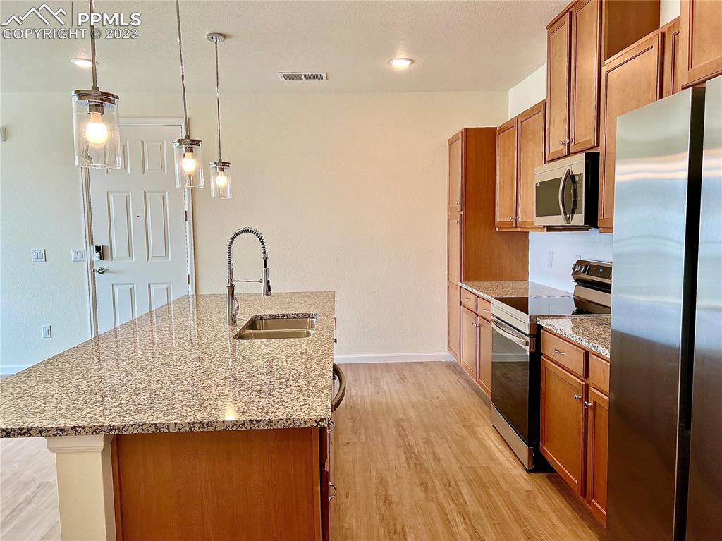 3865 Presidio Point, Unit 202 Colorado Springs, CO 80920 - Photo 5 of 30 a kitchen with stainless steel appliances granite countertop a sink a refrigerator and a wooden floor