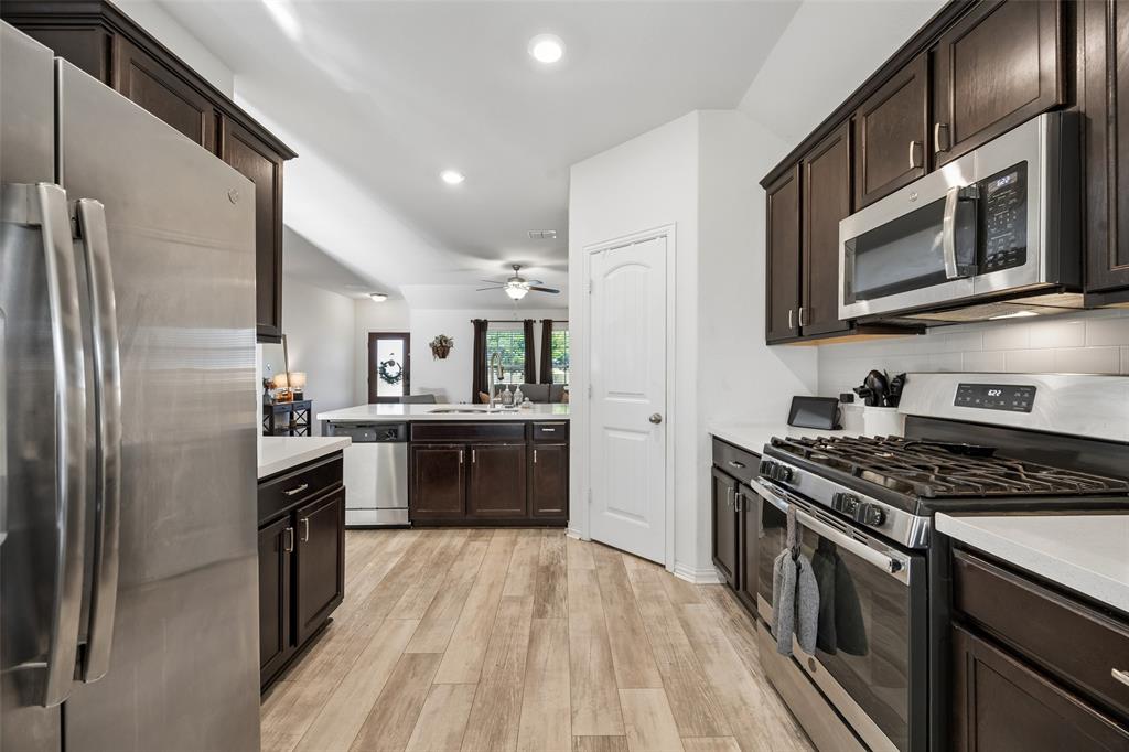 406 Madrone Lane Princeton, TX 75407 - Photo 8 of 30 Kitchen featuring dark wood cabinetry, stainless steel appliances, light-toned countertops, a subway tile backsplash, and wood-finish flooring