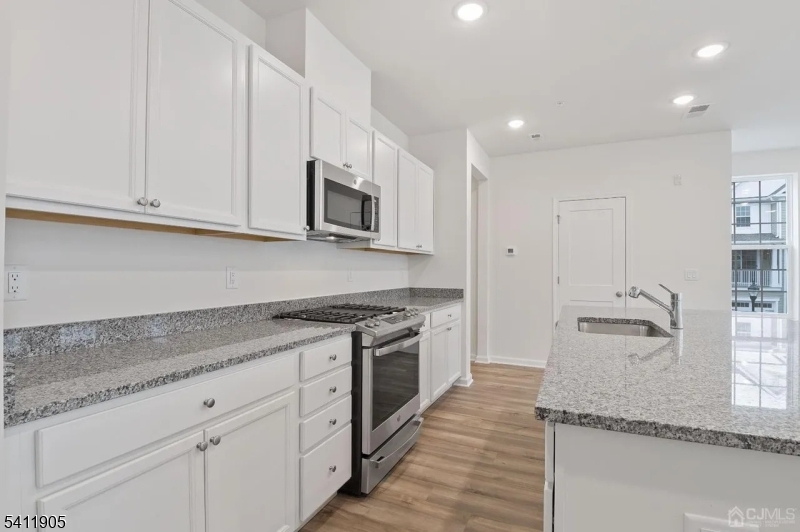 a kitchen with stainless steel appliances granite countertop a stove a sink and a microwave
