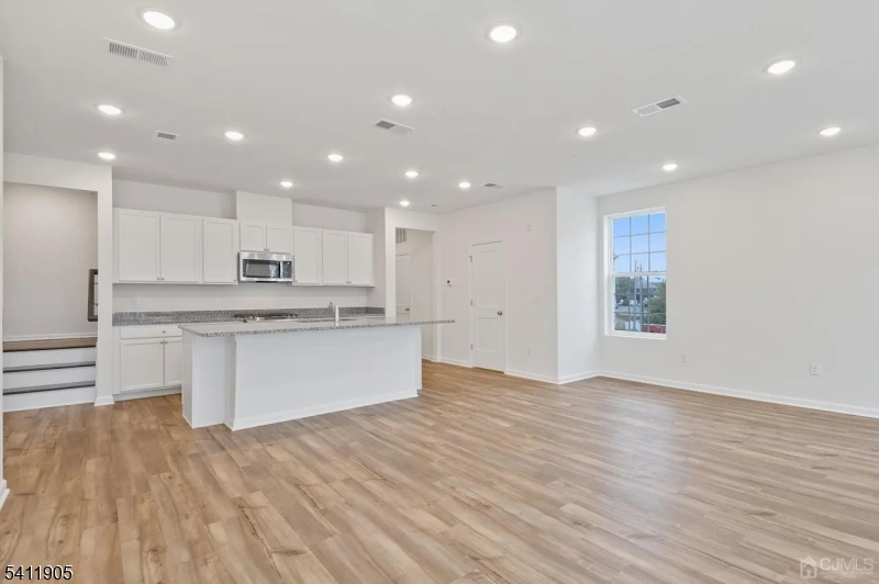 735 Station Road Dunellen, NJ 08812 - Photo 3 of 36 a large kitchen with kitchen island a sink dishwasher a stove and white cabinets with wooden floor