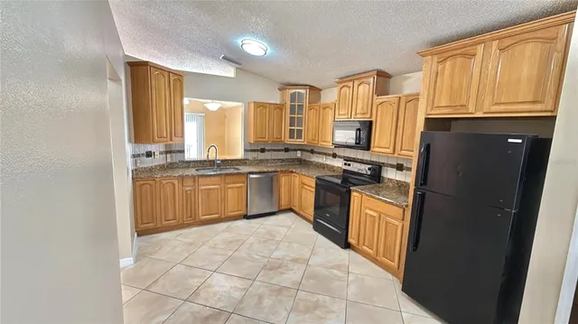 a kitchen with stainless steel appliances granite countertop a stove top oven a sink dishwasher and a refrigerator