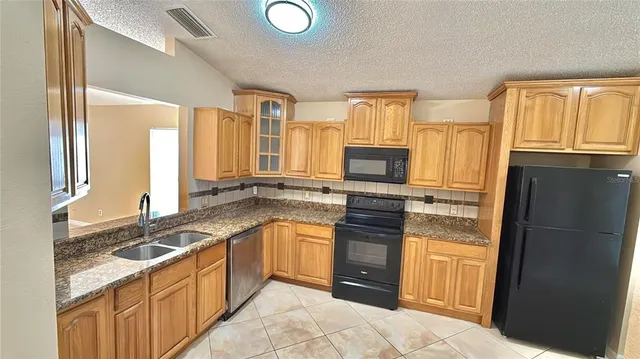 a kitchen with granite countertop a refrigerator stove top oven and sink