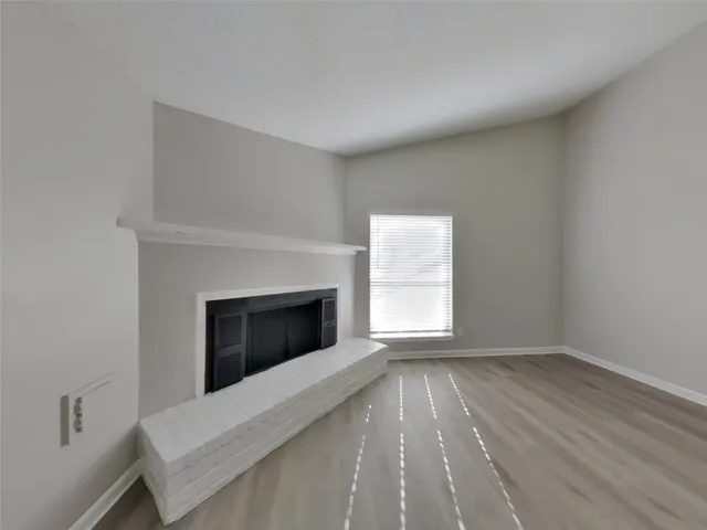 a view of an empty room with a fireplace and a window