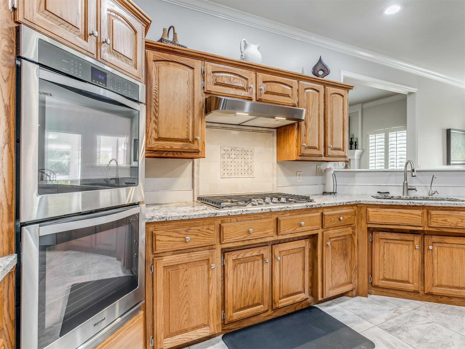 119 Mainsail Road Stigler, OK 74462 - Photo 14 of 52 Wood cabinetry with panel doors, stainless steel double wall oven, gas cooktop with stainless steel range hood, stone countertops, and tile flooring