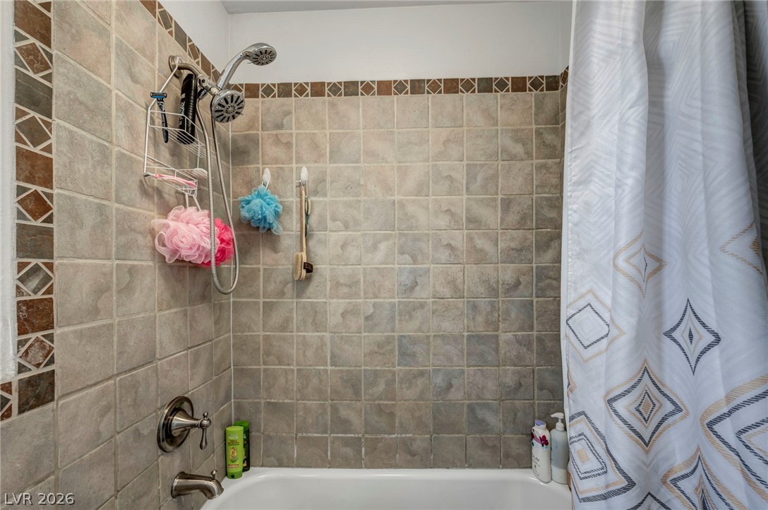 5882 Rio Tinto Way Las Vegas, NV 89110 - Photo 12 of 56 Ceramic tile surrounds a deep tub with a chrome shower fixture, promising relaxation.