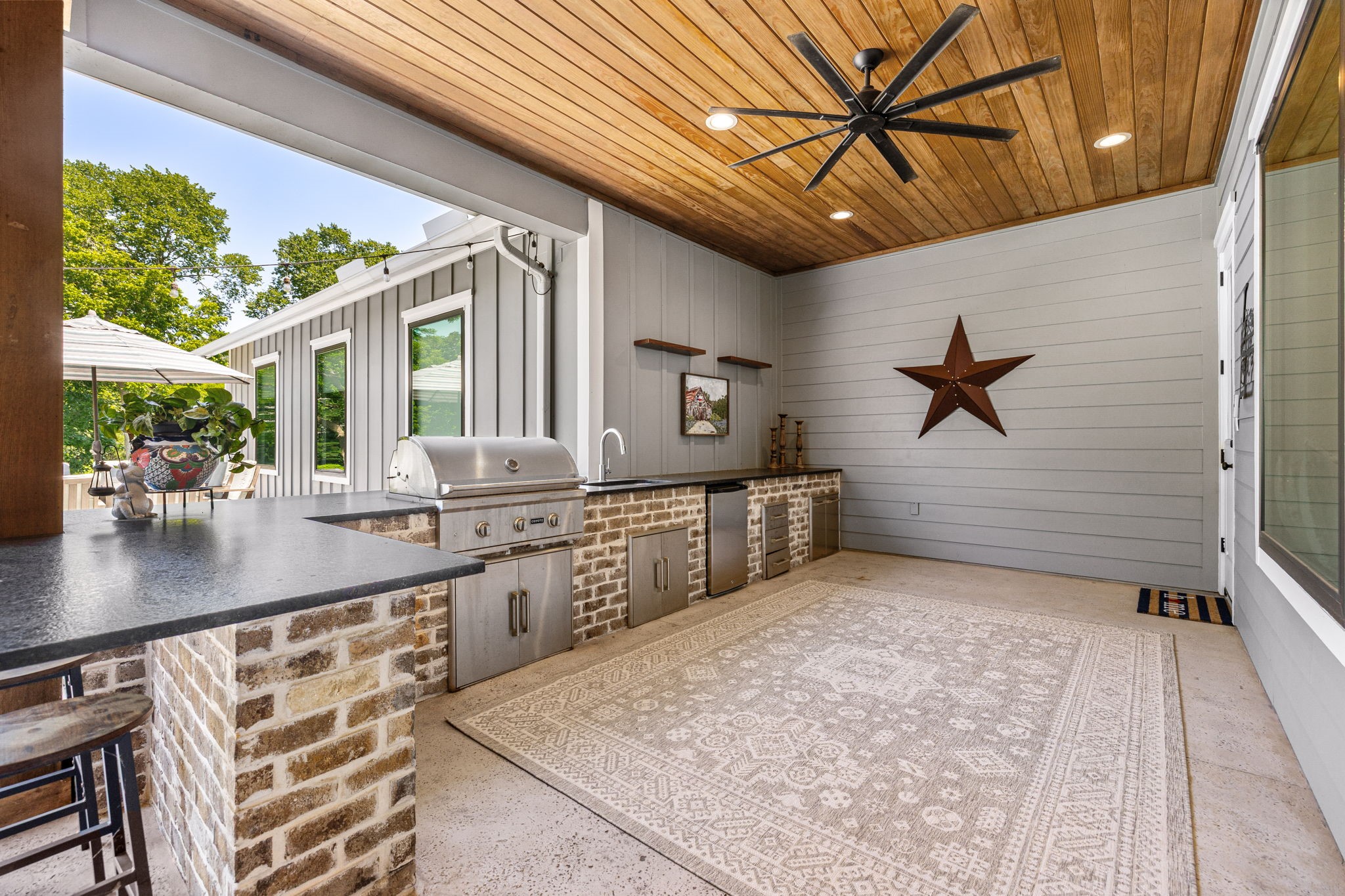 4311 Upper Oxbow Trace Fulshear, TX 77441 - Photo 36 of 49 Covered outdoor kitchen featuring a built-in grill, sink, refrigerator, and beautiful wood ceiling detail designed for effortless entertaining.