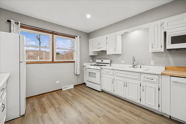 a kitchen with granite countertop white cabinets and white appliances