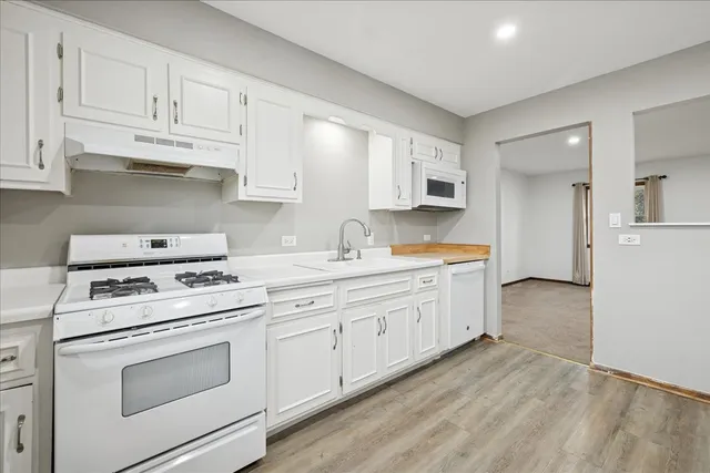 a kitchen with granite countertop white cabinets and white appliances