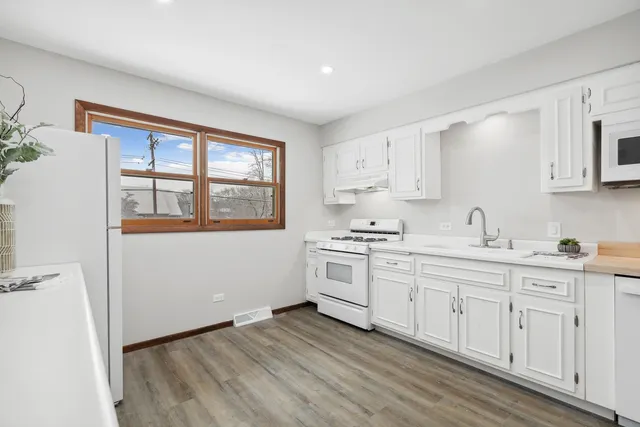 a kitchen with granite countertop white cabinets and white appliances