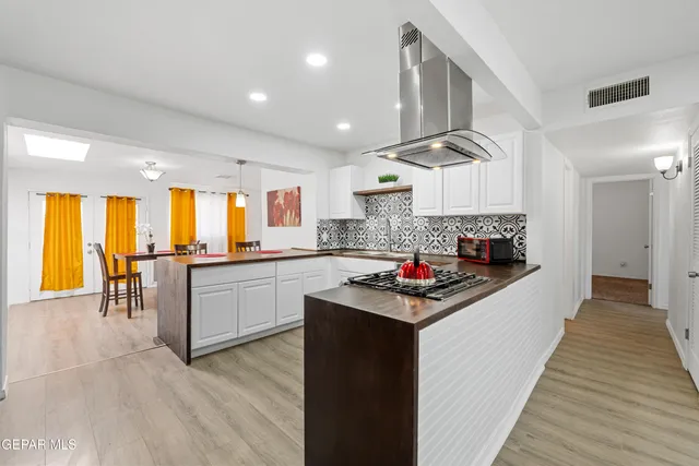 a kitchen with stainless steel appliances granite countertop a stove a sink dishwasher and a refrigerator with wooden floor