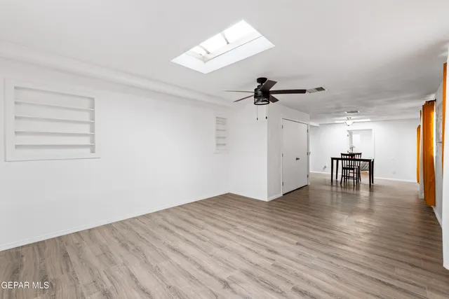 a view of empty room with wooden floor and ceiling fan