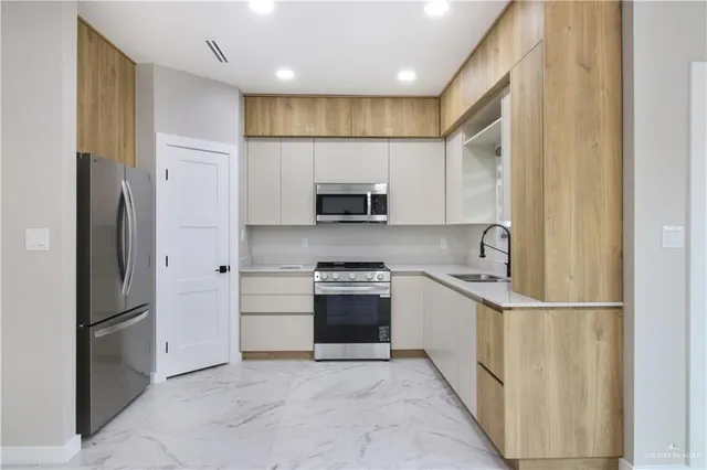 a kitchen with stainless steel appliances kitchen island granite countertop a stove and a sink with cabinets