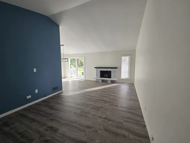 a view of empty room with wooden floor and fireplace