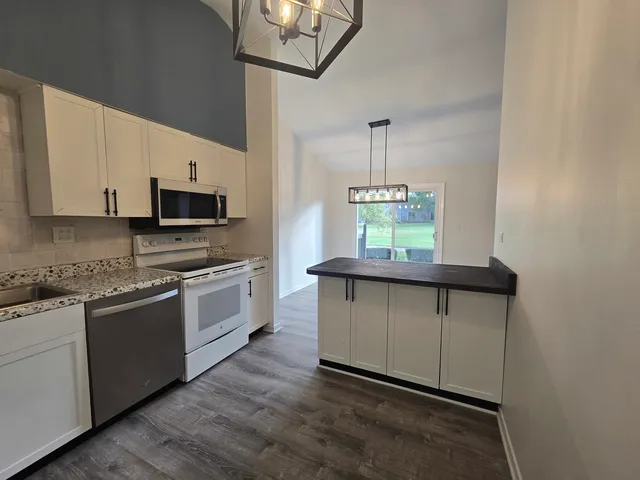 a kitchen with stainless steel appliances granite countertop a stove a sink and a microwave