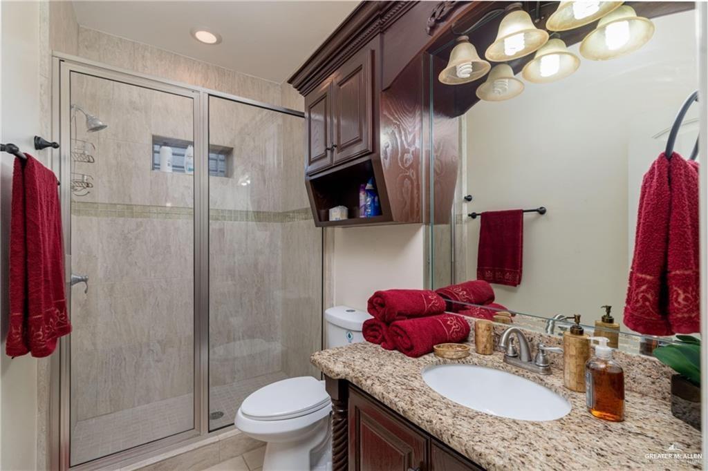 3210 South 5th Lane McAllen, TX 78503 - Photo 7 of 11 a bathroom with a granite countertop sink a toilet and a mirror