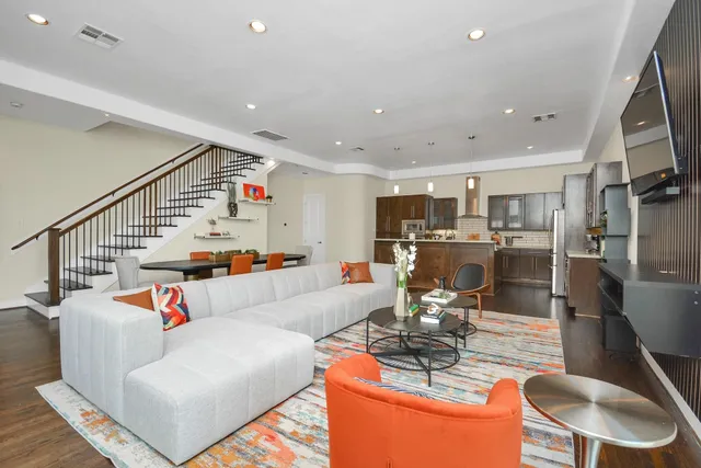 a living room with furniture kitchen view and a wooden floor