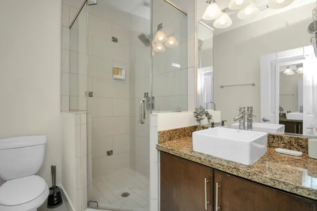 a bathroom with a granite countertop sink a toilet and shower