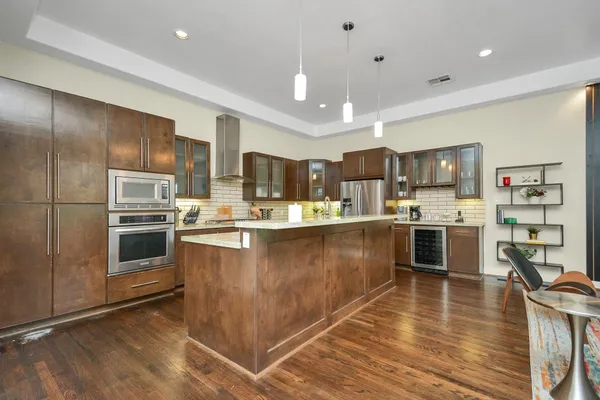 a kitchen with kitchen island a counter top space a sink stainless steel appliances and cabinets