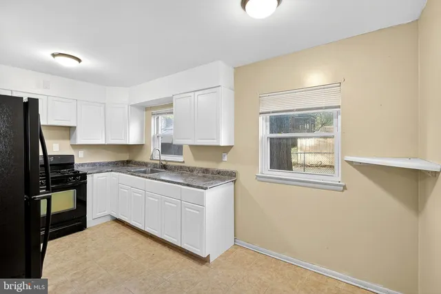 a kitchen with granite countertop a sink window and cabinets