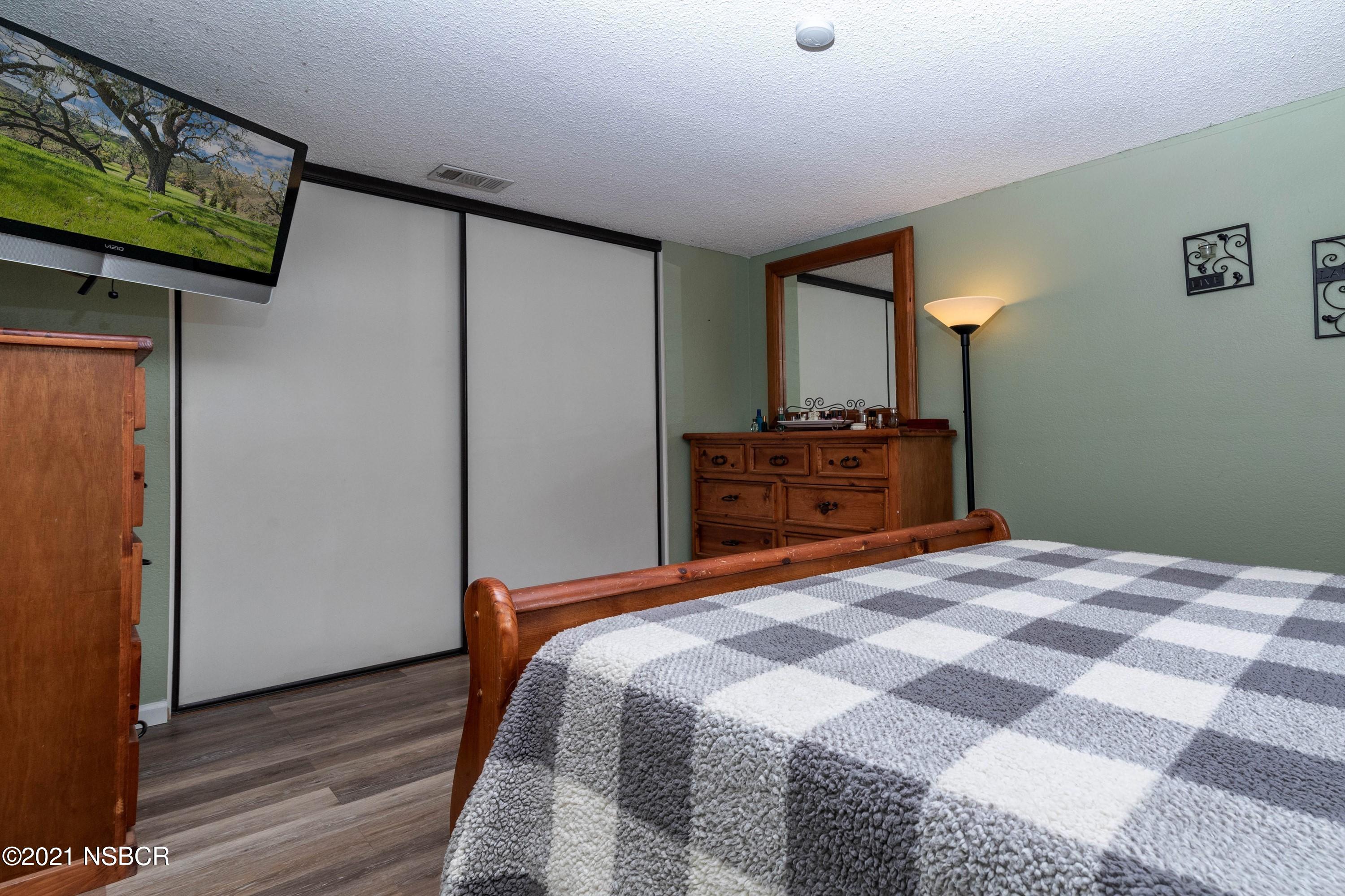 1117 Parkside Way Lompoc, CA 93436 - Photo 9 of 15 a bedroom with a bed a mirror on dresser and a wooden floor