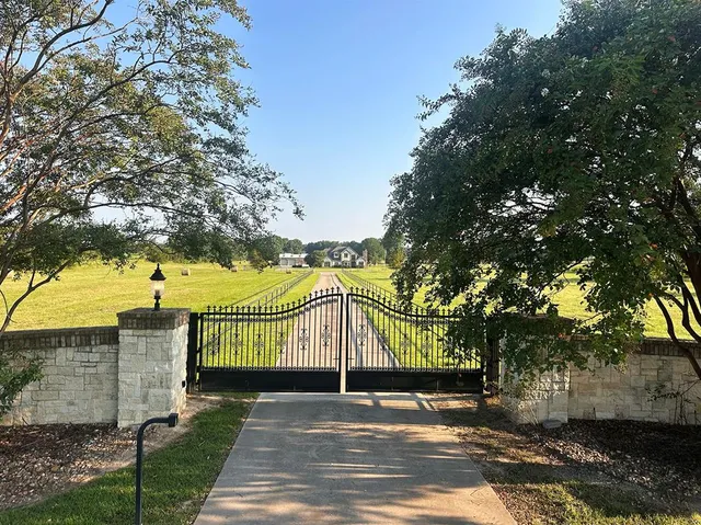 a view of a park with iron fence and large trees