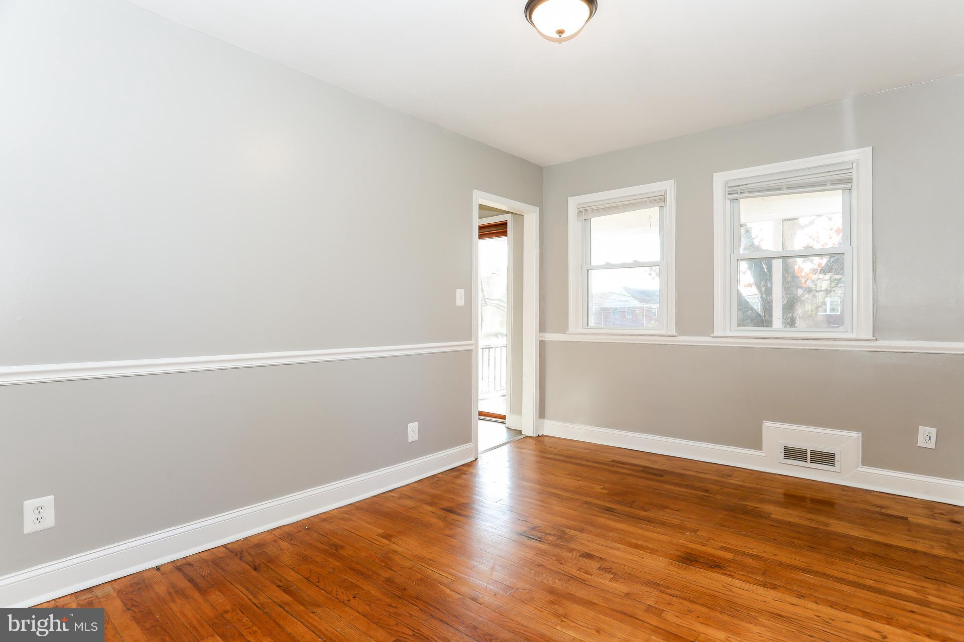 5911 Ayleshire Road Baltimore, MD 21239 - Photo 5 of 10 an empty room with wooden floor and windows