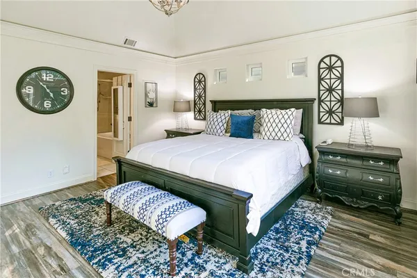 a bedroom with a bed a clock on dresser and a table