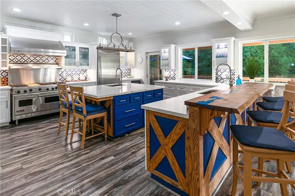 a kitchen with stainless steel appliances granite countertop a stove a sink dishwasher a dining table and chairs with wooden floor