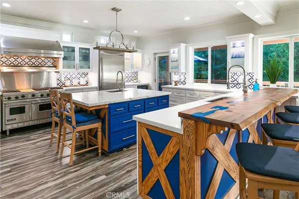 a kitchen with stainless steel appliances granite countertop a stove a sink dishwasher a dining table and chairs with wooden floor