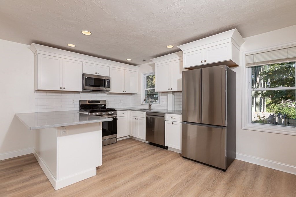4 Farragut Road, Unit 1 Ipswich, MA 01938 - Photo 4 of 13 a kitchen with a refrigerator a microwave a sink and cabinets