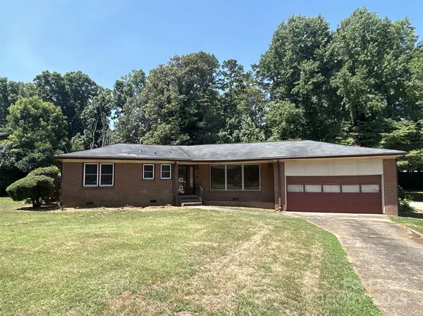 a front view of house with yard and trees in the background
