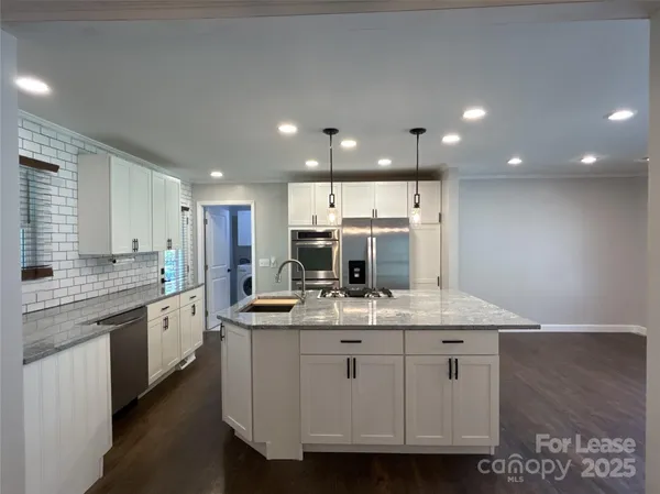 a large kitchen with stainless steel appliances kitchen island granite countertop a sink and cabinets