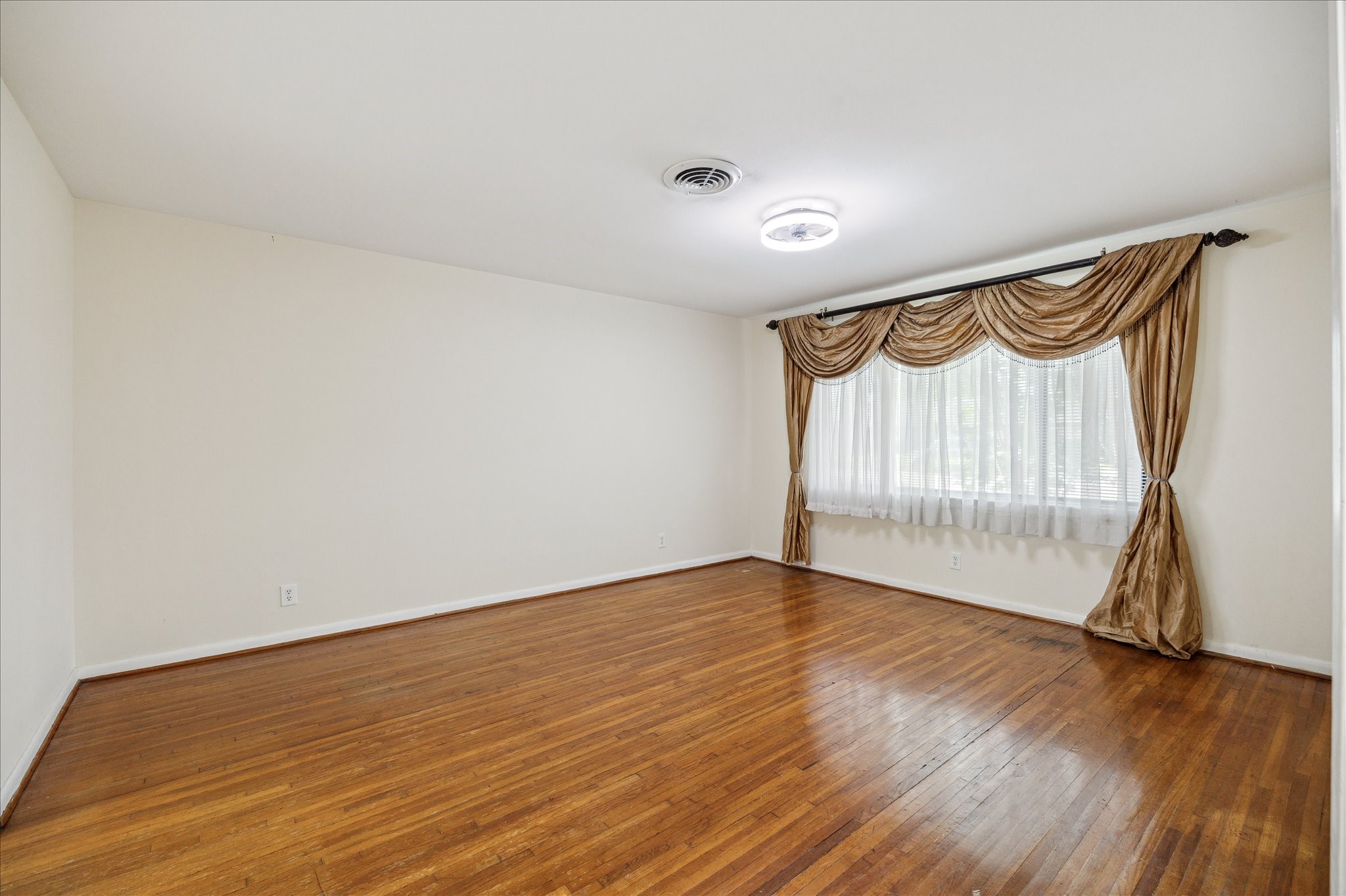 8907 Autauga Street Houston, TX 77080 - Photo 4 of 20 This room features hardwood flooring, neutral walls, and a large window with elegant drapes, providing plenty of natural light and a spacious feel.