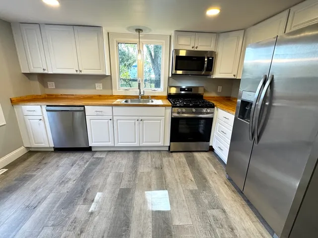 a kitchen with granite countertop a refrigerator stove top oven and sink