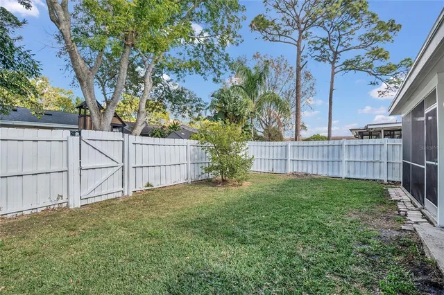 a view of a white house next to a yard with plants and trees