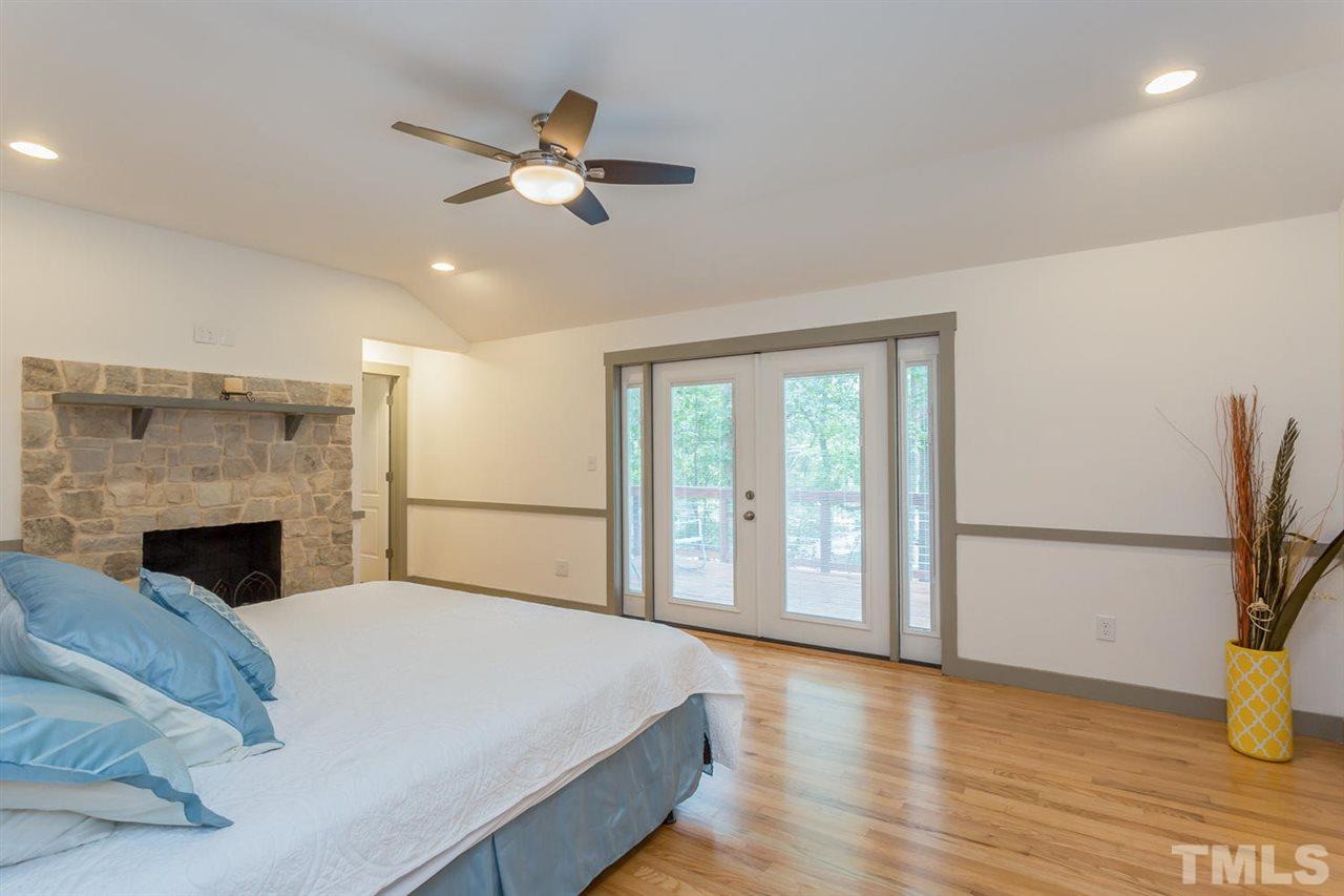 409 Stacy Street Raleigh, NC 27607 - Photo 14 of 25 a spacious bedroom with a large bed and a chandelier