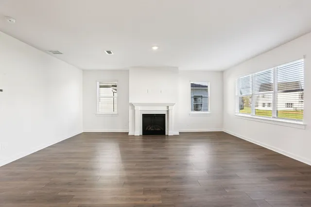 a kitchen with stainless steel appliances granite countertop a sink a stove a refrigerator and white cabinets with wooden floor