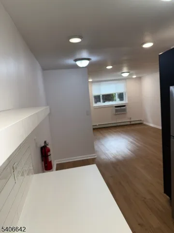 a view of kitchen and empty room with wooden floor
