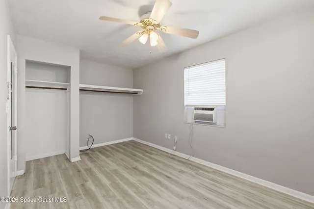 an empty room with a window and a ceiling fan