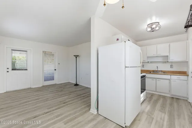 a view of a kitchen with refrigerator and white cabinets