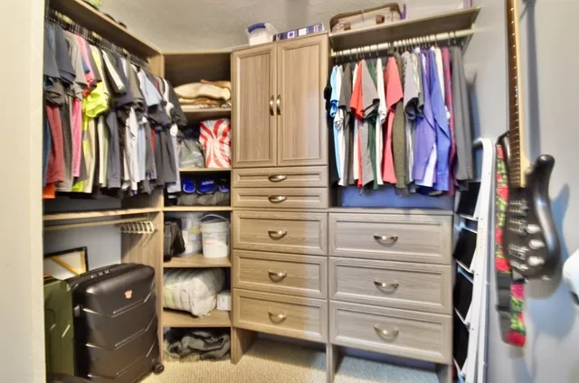 a view of walk in closet with clothes and shoes
