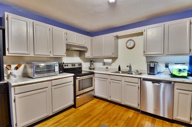 a kitchen with granite countertop white cabinets and white appliances