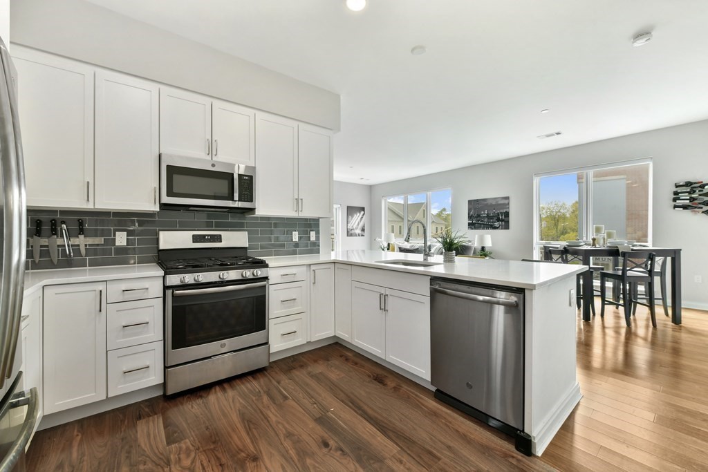 3531 Washington Street, Unit 226 Boston, MA 02130 - Photo 8 of 35 a kitchen with stainless steel appliances kitchen island granite countertop a stove a sink and a microwave