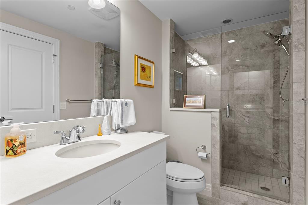 1325 Snell Isle Boulevard Northeast, Unit 711 St. Petersburg, FL 33704 - Photo 23 of 37 a bathroom with a granite countertop sink a toilet a shower and a mirror